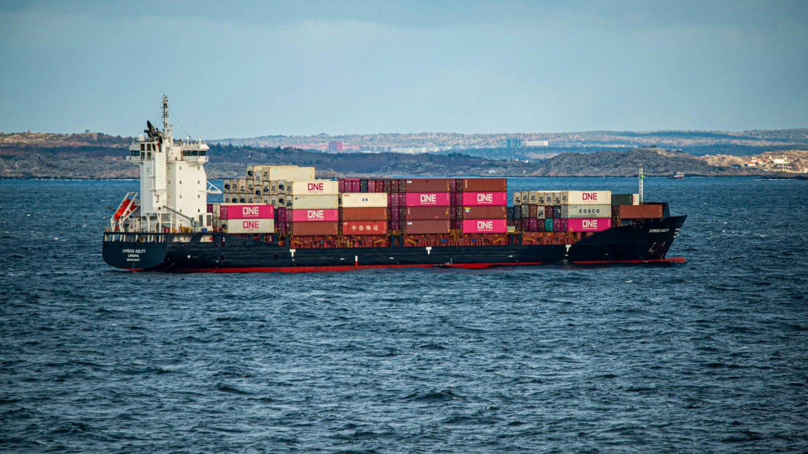A large container ship transports cargo across the open sea under a clear sky. Ideal for shipping and logistics themes.