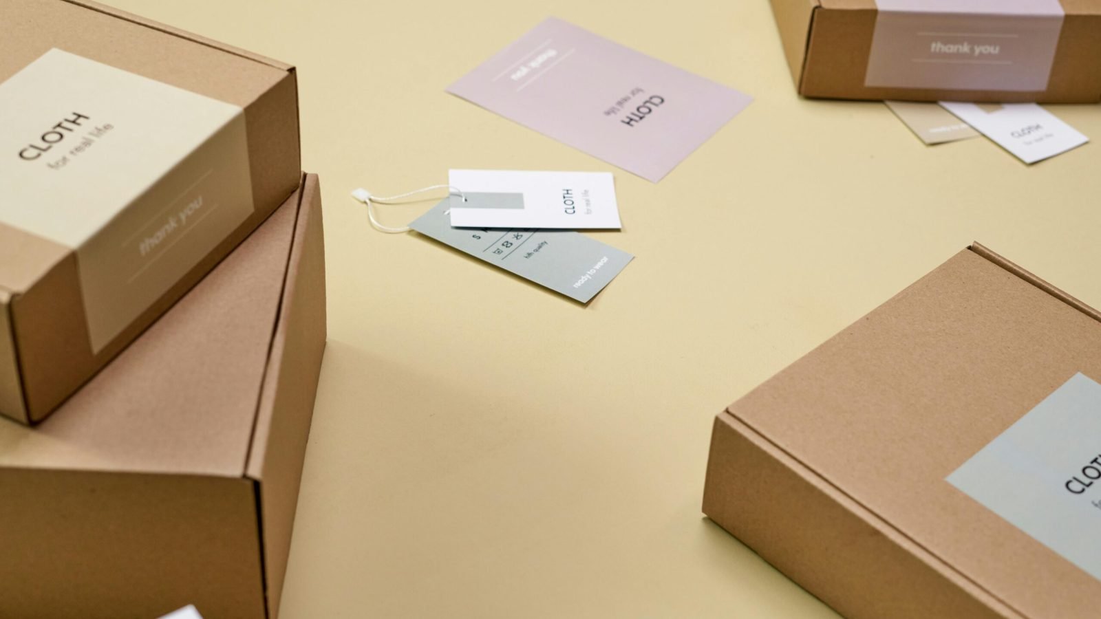 Simple and minimalist cardboard packaging boxes with labels on a yellow surface.